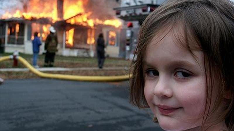 Zoë Roth como Disaster Girl sonriendo delante de un incendio controlado
