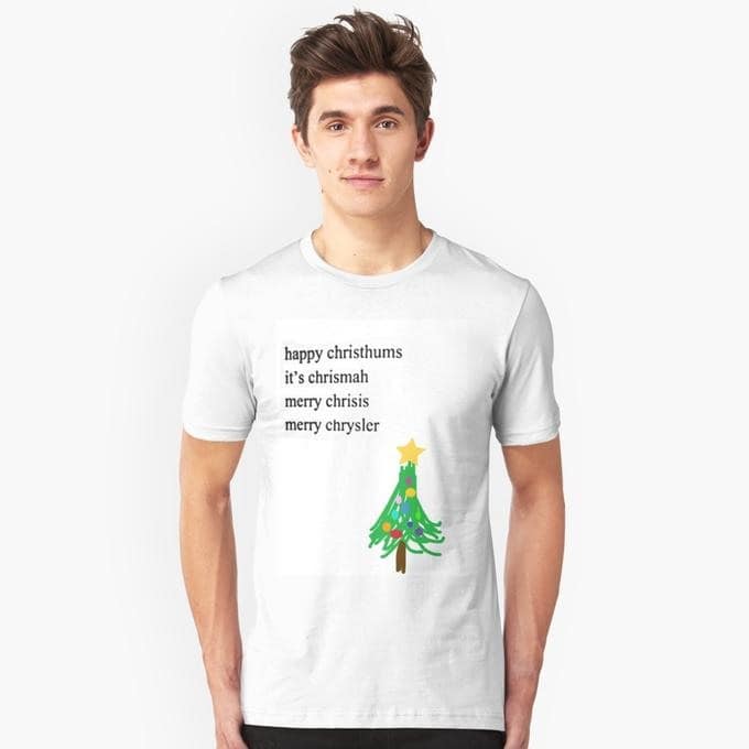A person models a white shirt with misspelled Christmas greetings, including “merry chrysler,” above a decorated Christmas tree.