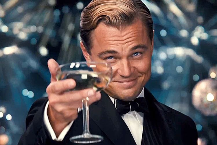 Leonardo DiCaprio as Jay Gatsby raising a glass in the classic toast meme